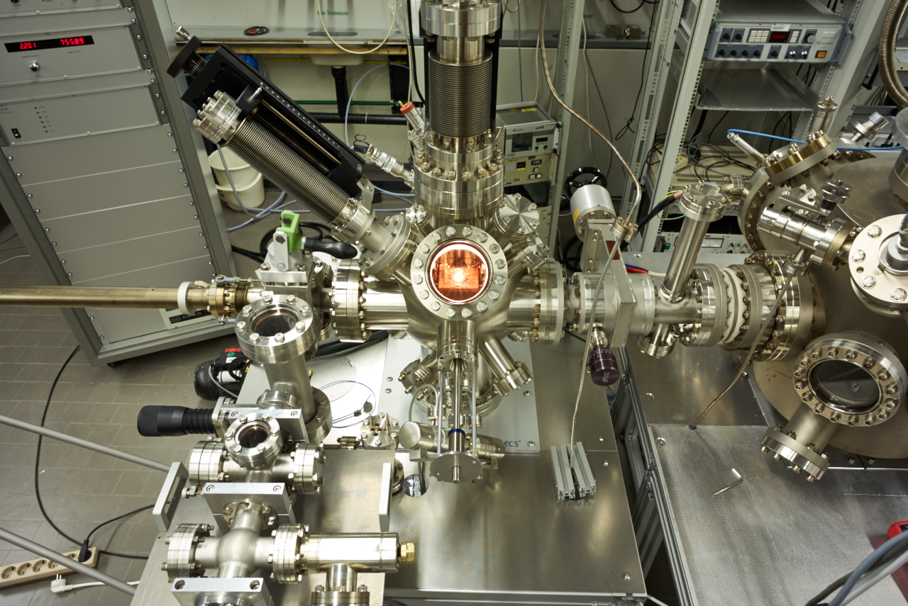 Fig. 1: STM chamber (center - with glowing filament for sample heating in the in situ STM) and the attached UHV system for LEED AES and surface preparation (right).